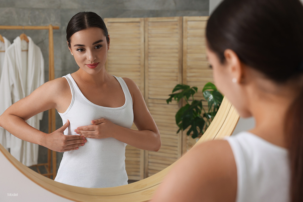 Young woman in a white shirt holding her breast